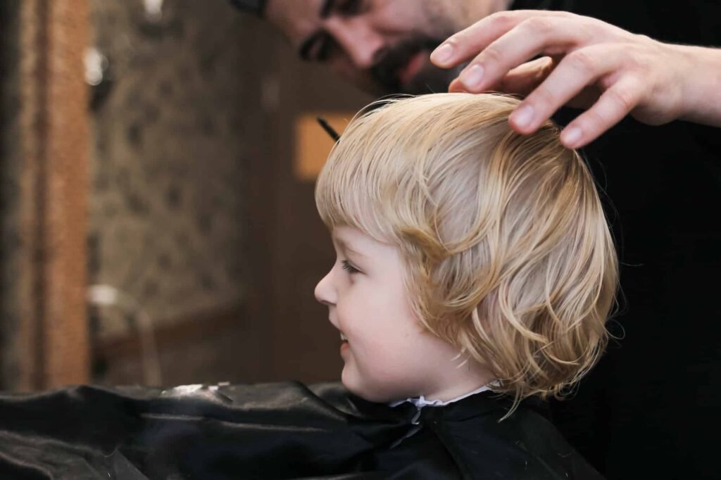 a-little-blonde-boy-is-trimmed-in-the-barbershop-bright-emotions-on-the-face-facial-expression-n